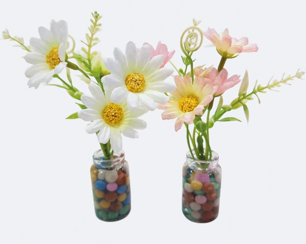 Glasvase mit Frühlingsblumen, Gräsern und buntem Dekor